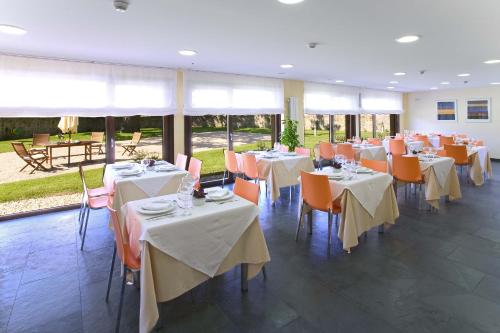 La CuevaPosada La Robla的一间设有白色桌子和橙色椅子的餐厅