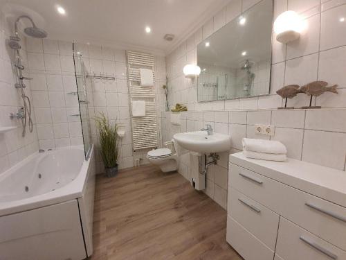 摩尔苏姆Hues-Sylt的白色的浴室设有水槽、浴缸和卫生间。