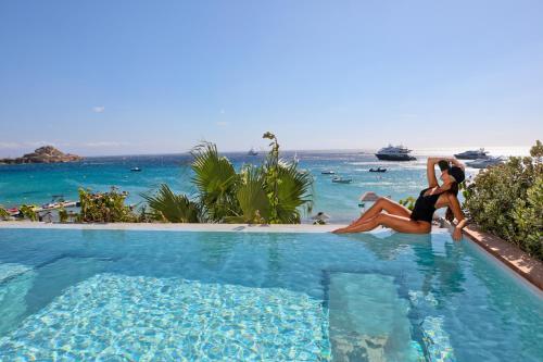 普拉迪斯亚罗斯Mykonos Dove Beachfront Hotel的两个女人坐在海边的游泳池里