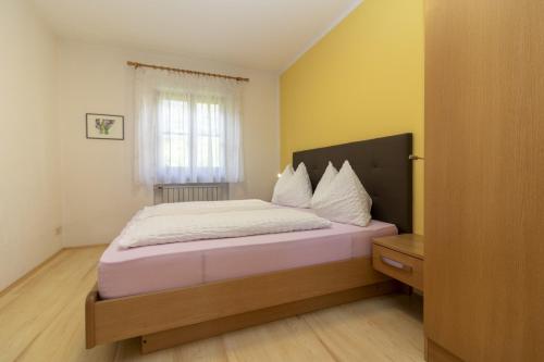 卡尔达罗Stompferhof Familienapartment的一间卧室配有一张带白色床单的床和一扇窗户。