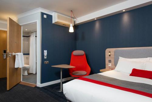 佩斯利快捷假日格拉斯哥机场酒店的酒店客房,配有一张床和一张红色椅子