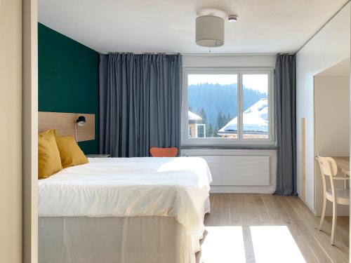 莱克斯Grüezi Laax Apartments的一间卧室设有一张大床和一个窗户。