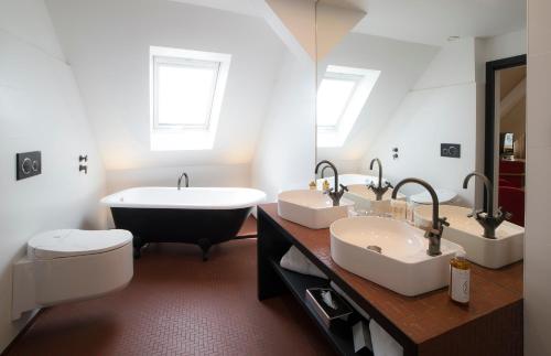 斯特拉斯堡HANNONG Hotel & Wine Bar的浴室配有两个盥洗盆和浴缸。