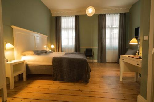 Sakskøbing萨克约滨酒店的一间卧室设有一张大床和两个窗户。