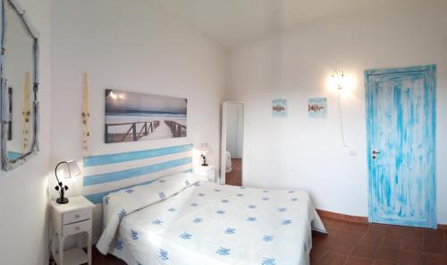 帕劳Le case di Stella Maris的一间白色卧室,配有一张床和一个蓝色的门