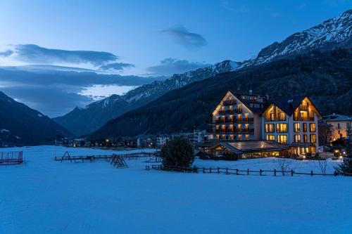 科涅Hotel Sant'Orso - Mountain Lodge & Spa的一座大建筑,位于一个有山的雪地