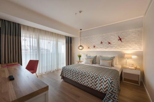 凯麦尔Akra Kemer - Ultra All Inclusive的配有一张床、一张书桌和一扇窗户的酒店客房