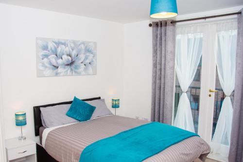 德比Grand Central Friar Gate Deluxe Apartments的一间卧室配有一张带蓝色枕头的床和一扇窗户。