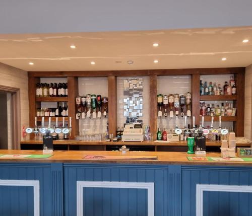 伯明翰The Aston Inn的一间酒吧,内配蓝色橱柜和酒瓶