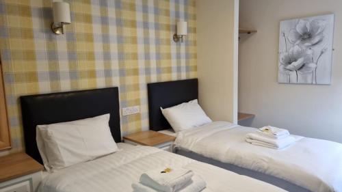 伯明翰The Aston Inn的配有2张床的客房内配有白色床单和毛巾
