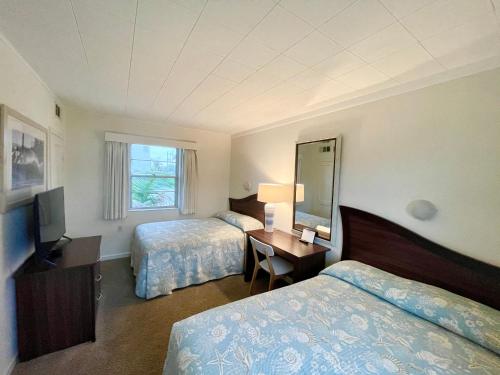 可可比奇冲浪工作室海滩度假公寓式酒店的酒店客房配有两张床和一张带镜子的书桌