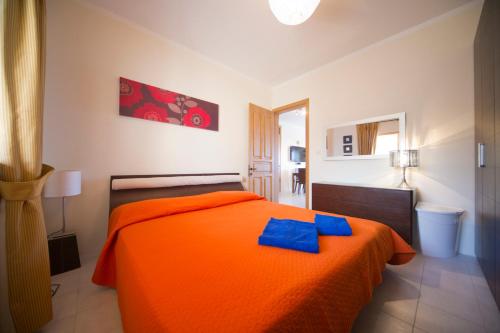 圣保罗湾城阿斯科特海滩公寓的一间卧室配有橙色床和蓝色毛巾