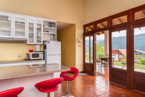 奥罗西Casa Bartzis, Close to Orosi and Tapanti National Park的厨房配有红色椅子和带冰箱的柜台