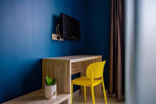 吉隆坡BEEZ Hotel Kuala Lumpur的一张带黄椅的桌子和蓝色墙壁上的电视
