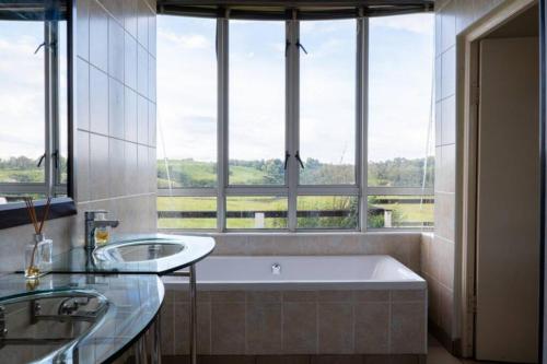 Van ReenenHighlands Farm House的一间带两个盥洗盆和一个带窗户的浴缸的浴室