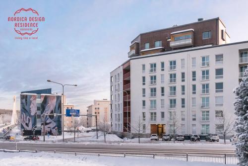 罗瓦涅米Nordica Design Residence Rovaniemi的街道旁的雪地里一座白色的大建筑