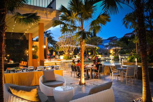 南芭堤雅Kudos Parc Pattaya的棕榈树餐厅,餐桌旁的座位
