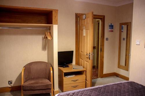 梅尔罗斯车站酒店&餐厅的一间卧室配有一张床、一把椅子和电视