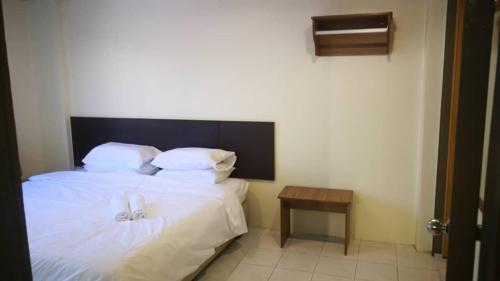 邦咯Pangkor staycation apartment的一间卧室配有一张带白色床单和一张桌子的床。