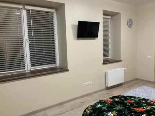 罗夫诺LUX apartment & центр,ЖК Театральний的卧室设有2扇窗户,墙上配有电视。