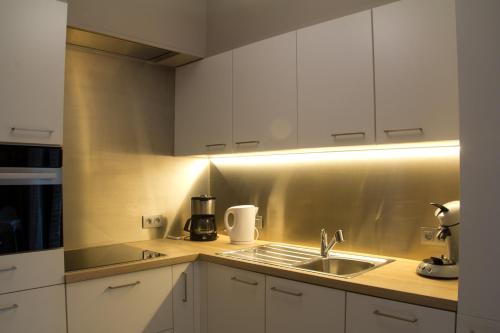 博尔赫隆't Gillebroek的厨房配有白色橱柜和水槽