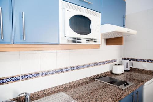 卡门港蓝色海洋海滩公寓式酒店的厨房配有蓝色橱柜和微波炉