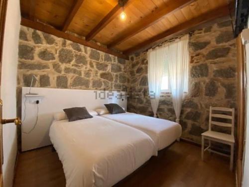 阿维拉Casa Serapio的卧室配有一张石墙内的大床