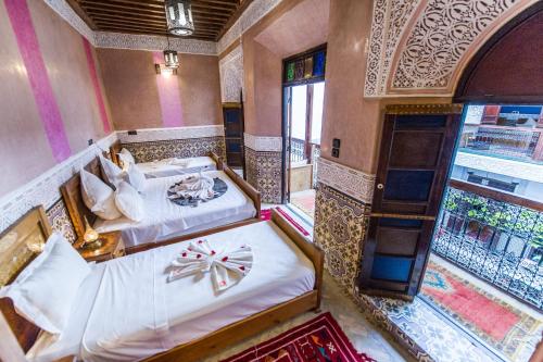 马拉喀什Riad Atlas Mejbar的一间带两张床的卧室和一个阳台