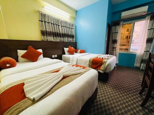 博卡拉Rosemary Homes Pokhara的酒店客房 - 带两张带橙色枕头的床