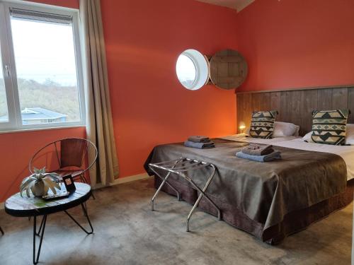 东福尔讷Beach Hotel Oostvoorne的卧室设有红色的墙壁、一张床和椅子