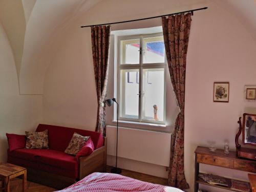 斯拉沃尼采Apartmány na Trojmezí, byt Leopold的一间卧室设有红色的沙发和窗户。