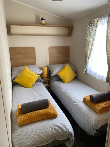 SwarlandDixons den的小客房内的两张床,配有黄色枕头