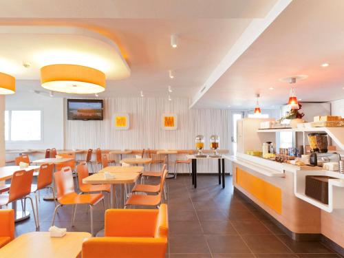 塞尔吉Ibis Budget Cergy St Christophe的一间带桌椅的餐厅和一间酒吧