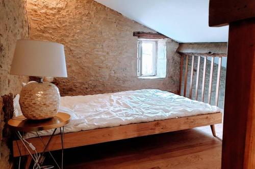 Saint-SèveGITE AU COEUR DE LA CAMPAGNE的一间卧室配有一张床和一张桌子上的台灯