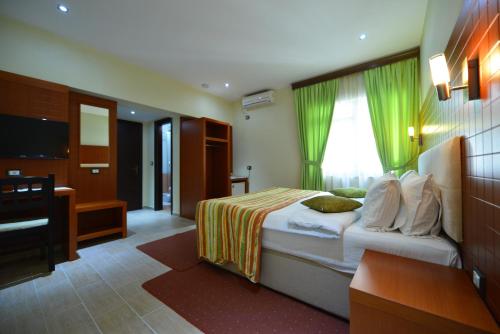 地拉那City Hotel的一间卧室配有一张带绿色窗帘的床和电视。