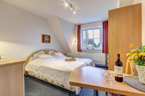 洛丁Haus Ostseeglück - Ferienwohnung Mittagssonne mit Gemeinschaftssauna的一间卧室配有一张床和一张桌子及一瓶葡萄酒
