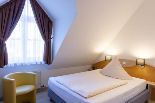 开姆尼茨阿尔特穆尔酒店的卧室配有床、椅子和窗户。
