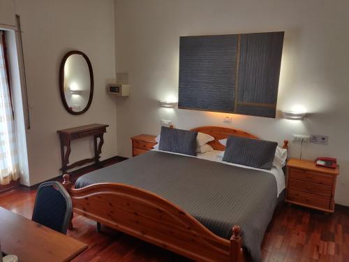 纳托鲁斯提契洛酒店的一间卧室配有一张大木床和镜子