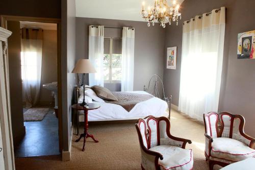 圣吉尔Mas de la Fosse的一间卧室配有一张床、两把椅子和一个吊灯