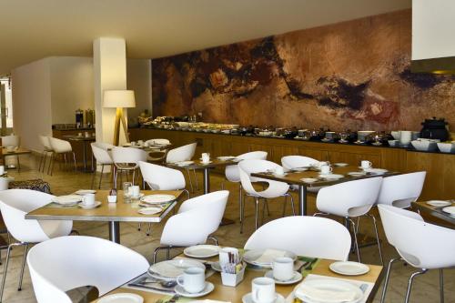 莱昂莱昂庆典酒店的用餐室配有桌子和白色椅子
