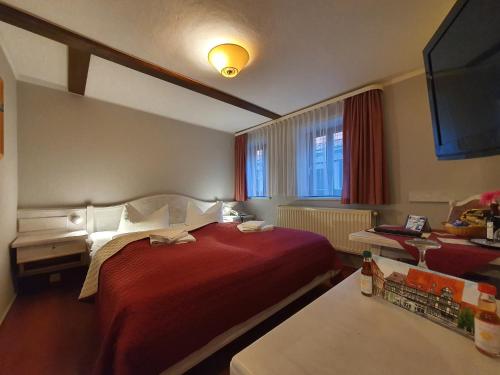 奎德林堡Hotel Zur Goldenen Sonne的酒店客房设有红色的床和电视。