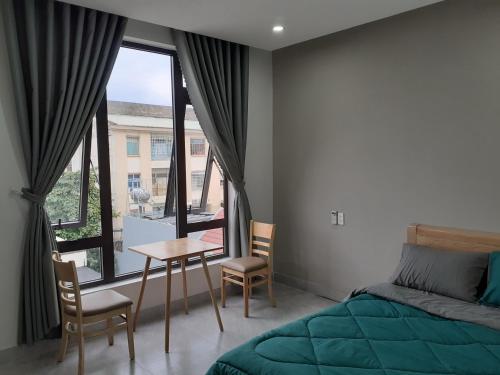 岘港Duc Hanh Apartment的一间卧室配有一张床、一张桌子和一个窗户。