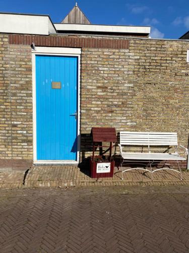 哈林亨Studio Chilltime Harlingen的砖楼旁边的一扇蓝色门和长凳
