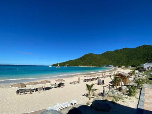 Anse Marcel From Paris to SXM - luxury next to Anse Marcel Beach的海滩上设有椅子和遮阳伞,还有大海