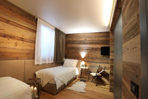 布勒伊-切尔维尼亚Petit Chalet Blanc Cervinia的一间卧室配有两张床、一张桌子和一台电视。