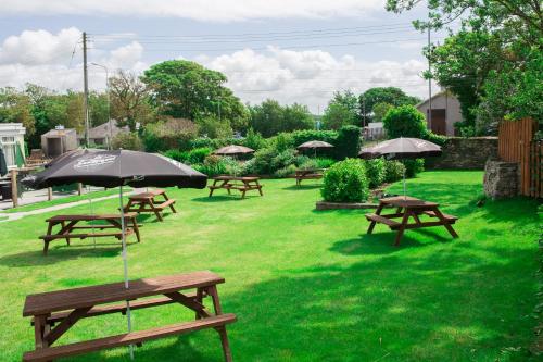 瓦利The Valley Hotel, Anglesey的一组野餐桌,在草地上放一把伞