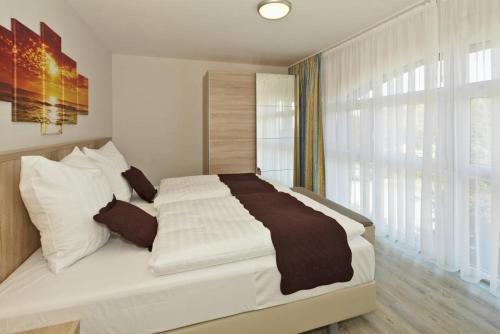 施托尔佩奥夫乌塞多姆Der Landhof Schwalbennest LH-204的卧室配有一张带白色床单的大床和窗户。