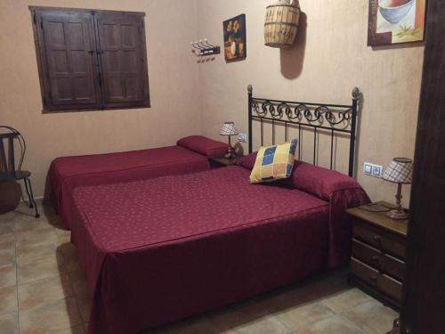 阿尔卡拉德尔胡卡尔Casas Rurales Hoz del Júcar的卧室内的两张床,配有红色床单