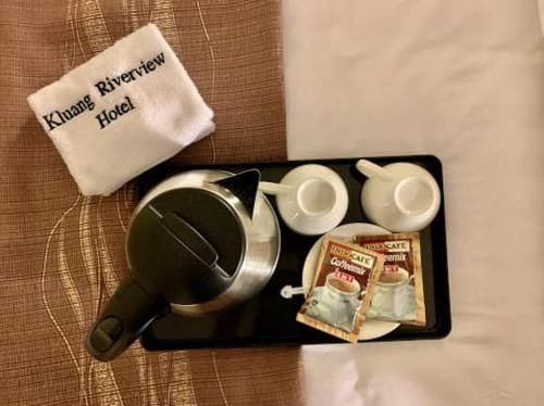 居銮KLUANG RIVERVIEW HOTEL的盘子,盘子上放着杯子,茶壶和一些食物