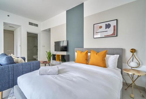 迪拜Stella Stays Pristine Studio Dubai JVC Large Terrace的卧室配有带橙色枕头的大型白色床
